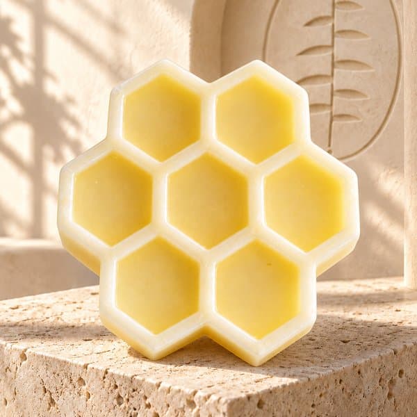 Organic Honey Soap, a yellow honeycomb bar on a stone plinth in the branded cream studio